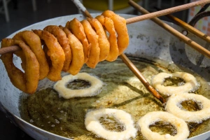 Picarones friéndose en sartén grande con abundante aceite