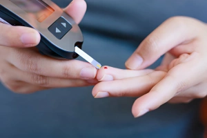 persona utilizando el glucómetro para medirse la glucosa en sangre